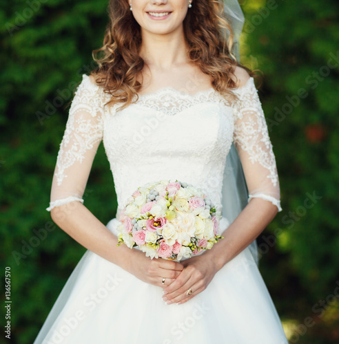 Beautiful bride holding a wedding bouquet in her hands