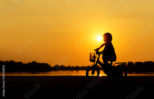 Little girl riding bike, Asian kid ,Silhouette a kid at the suns