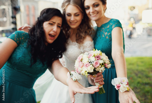 Happy beautiful bride with bridesmaids posing outside