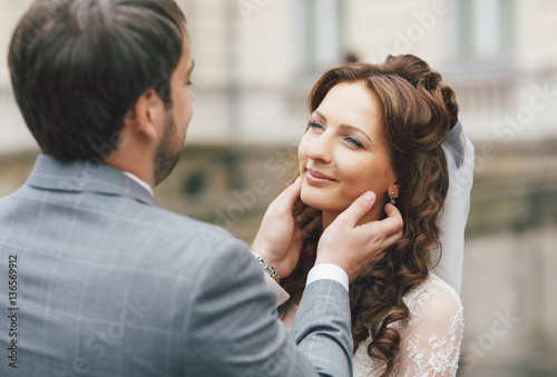 Groom is holding a face of the beautiful bride