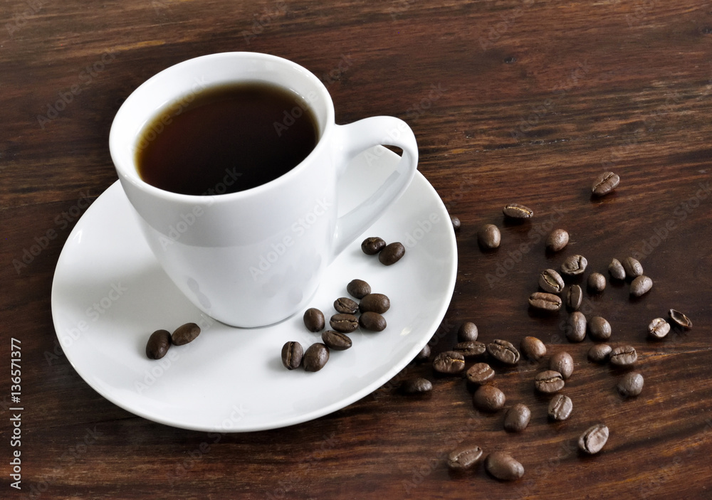 Breakfast scene with coffee cup and coffee beans on a wooden table. Morning scene with hot coffee.