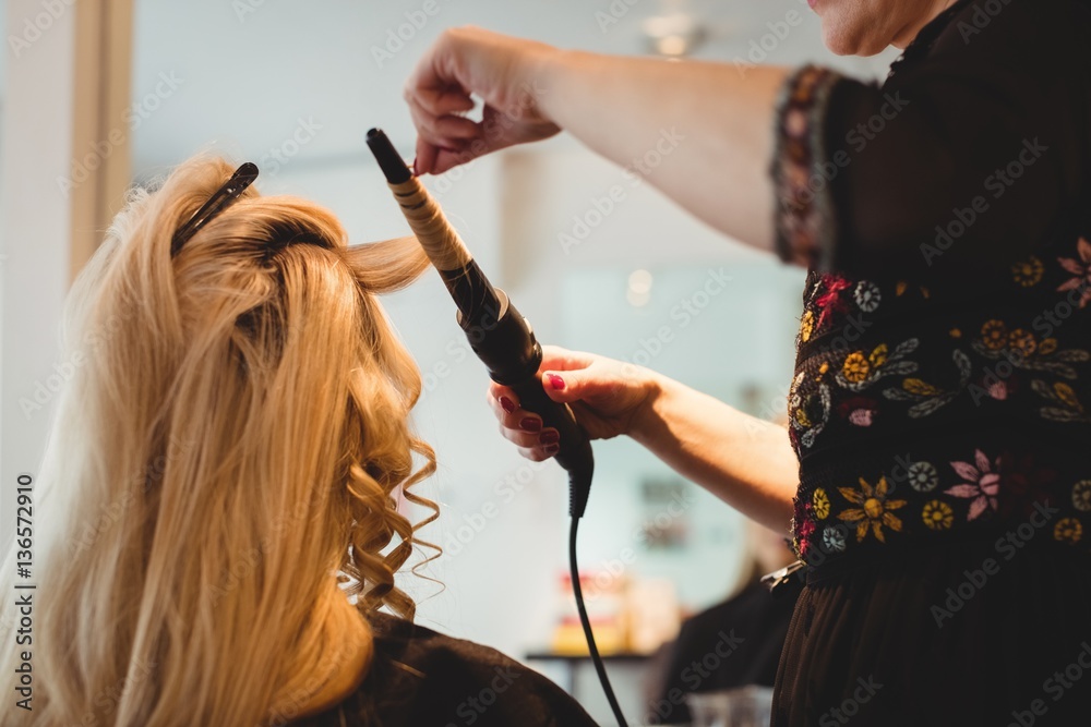 Female hairdresser styling clients hair in salon Female hairdresser styling clients hair in salon