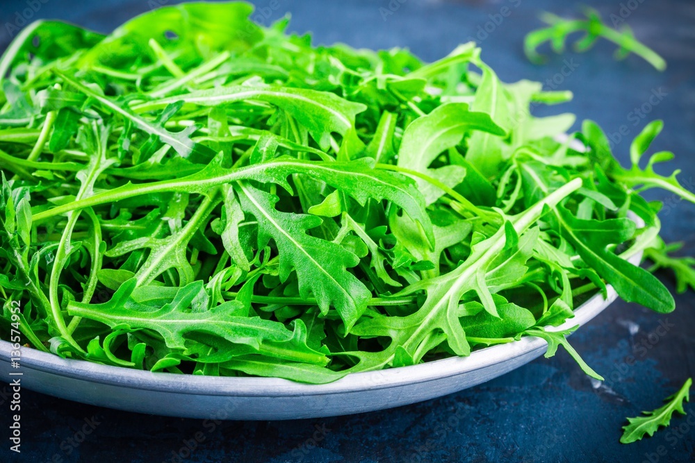 Fresh organic arugula leaves in bowl closeup Fresh organic arugula leaves in bowl closeup
