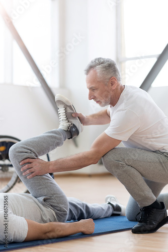 Powerful orthopedist stretching the handicapped in the gym