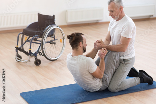 Schilderij op canvas Skilled orthopedist assisting the disabled in the gym