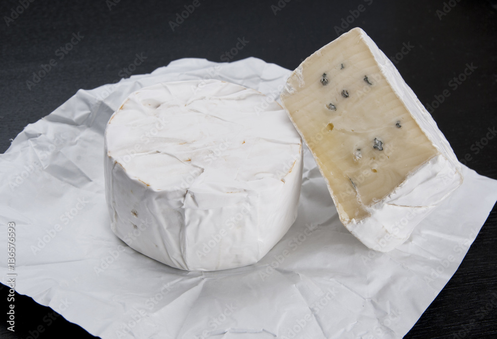 Soft cheese on white wrapping paper and black table Soft cheese on white wrapping paper and black table