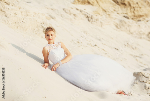 Pretty bride is lying on the white sand