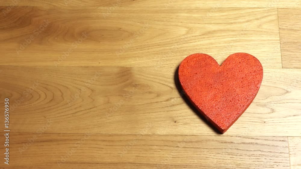 Elegant female hands putting two red heart shapes on wooden table Elegant female hands putting two red heart shapes on wooden table