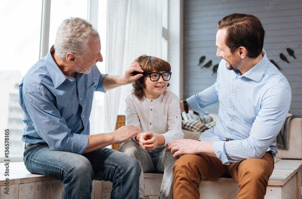 Obraz premium Nice aged man fixing his grandsons glasses