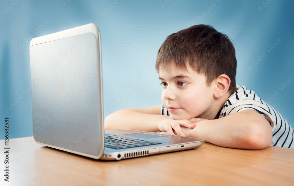 seven years old child in glasses sitting with a laptop at table seven years old child in glasses sitting with a laptop at table