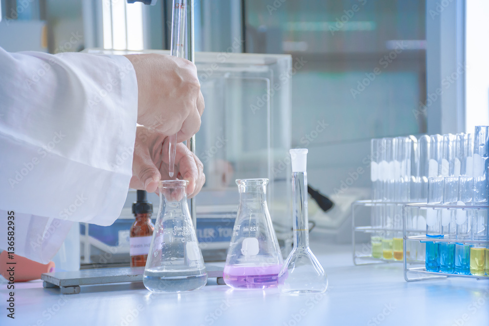 Scientist dropping sample in flask Scientist dropping sample in flask