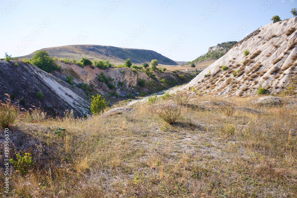 View on hills and fields from a limestone cliff at a quarry under a beautiful blue sky, abandoned white stone career, in fetesti village, Moldova