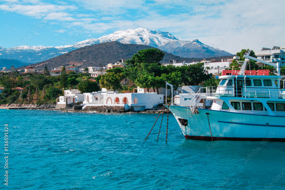 Cruise boat with snowy mountain and blue sky in background, Agios Nikolaos, Crete Island, Greece