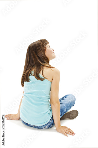 Rear view of little girl sitting on floor. Isolated on white background 