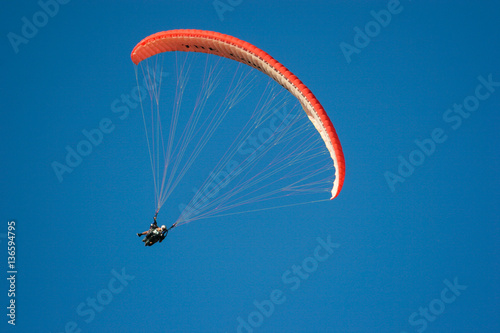 Paraglider flying across blue sky on a summer's day