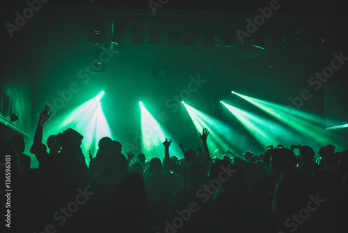 Hands in the air in a club with green lights