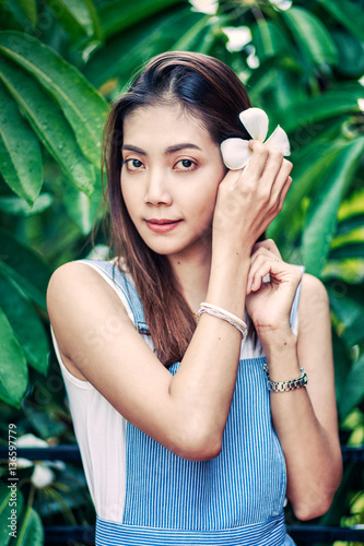 asian beautuful woman put Plumeria flower in her hair