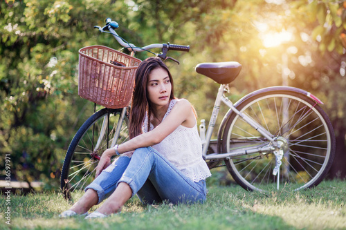 asian beautuful woman seating in park with bicycle