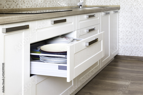 Opened kitchen drawer with plates inside, a smart solution for kitchen storage and organizing. 