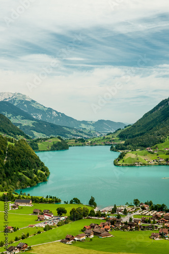 Aerial view of lake with mountains and green meadows in Switzerland 