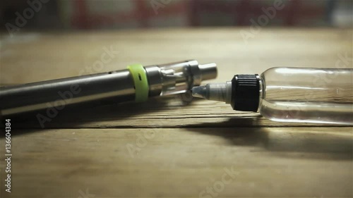 Unsharpness footage with electronic cigarette and a bottle with liquid for background. photo