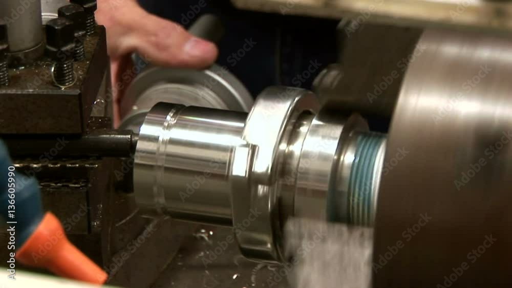 A metal working using a metal lathe on a piece of stainless steel tubing.