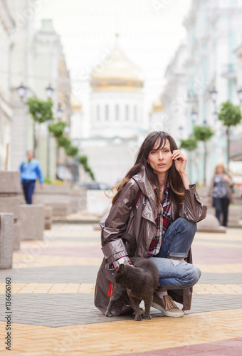 beautiful woman walking with a cat in the city