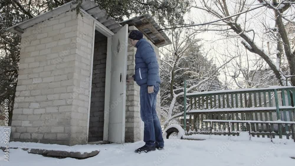 The man left and closed the door in the brick toilet in the village in winter The man left and closed the door in the brick toilet in the village in winter