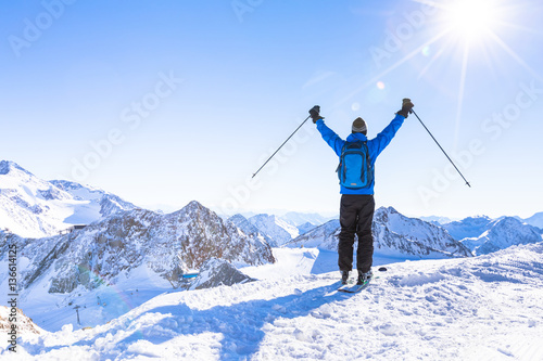 Back view of a happy skier with raised hands