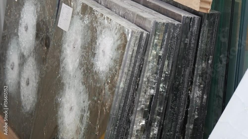 a Specialist Counts Sheets of Bulletproof Mirror Glass, Made of Several Layers, With Round Cracks and Fractures From the Bullets, Being Shot by a Steadicam Camera