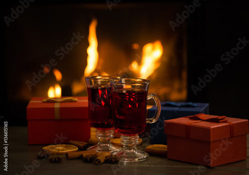 Hot wine in glass in front of fireplace with Christmas gifts