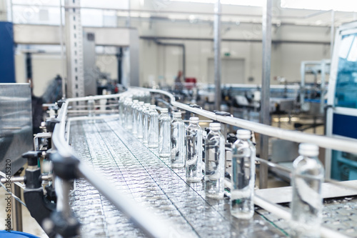 Water factory - Water bottling line for processing and bottling pure spring water into small glass bottles. Selective focus.