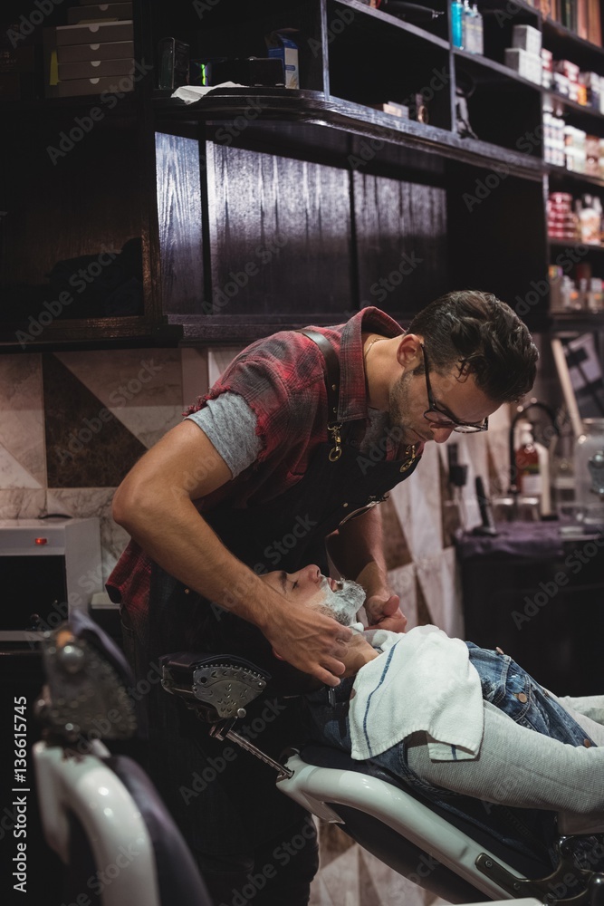 Barber applying cream on clients beard Barber applying cream on clients beard