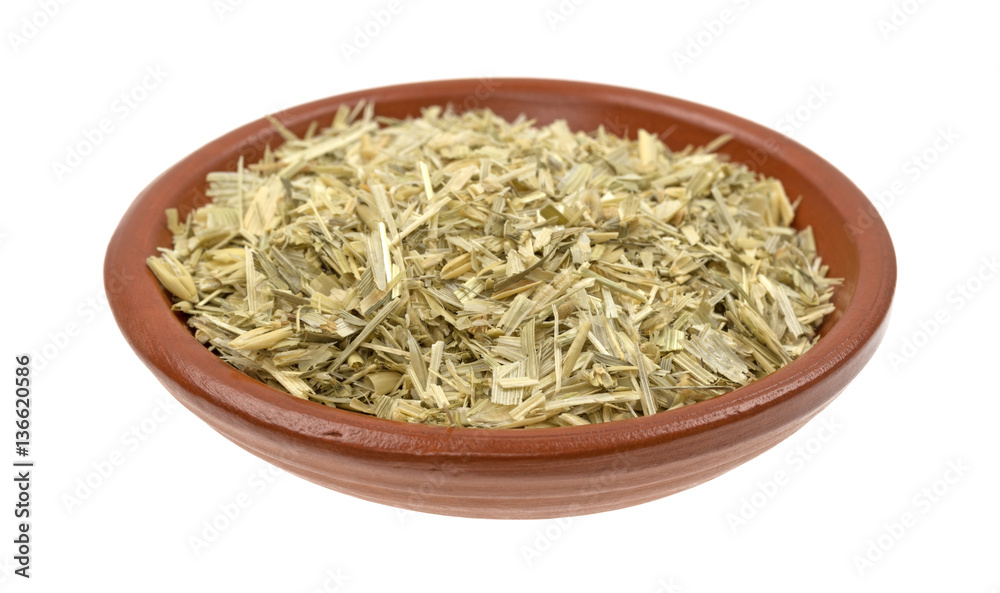 Bowl of dried and shredded oatstraw herb isolated on a white background.