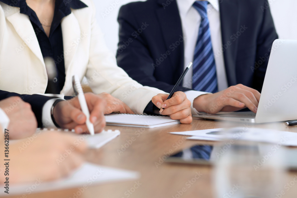 Group of business people at meeting, close up of human hands in work with pen and papers Group of business people at meeting, close up of human hands in work with pen and papers