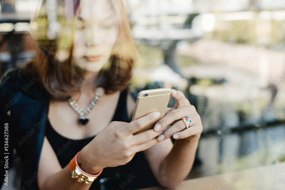 Woman using smart phone in a cafe,image of young woman sitting at a table with a coffee using mobile phone.