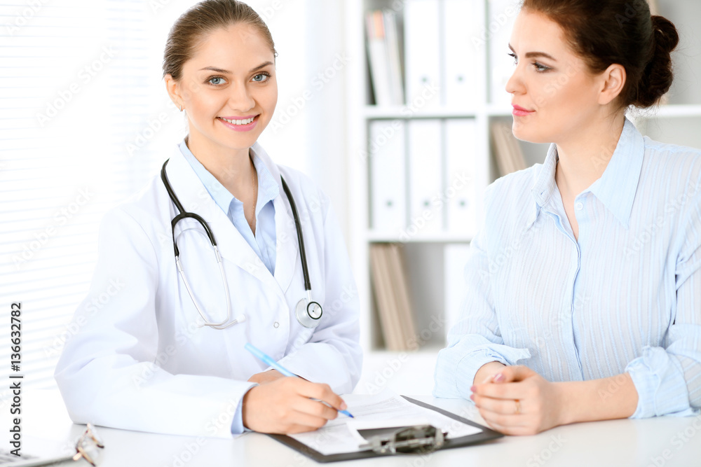 Friendly smiling doctor and patient sitting at the table. Very good news and high level medical service concept. Friendly smiling doctor and patient sitting at the table. Very good news and high level medical service concept.