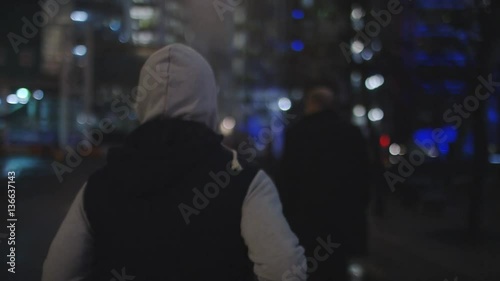 4K Camera follows a man running in the city at night, in slow motion 