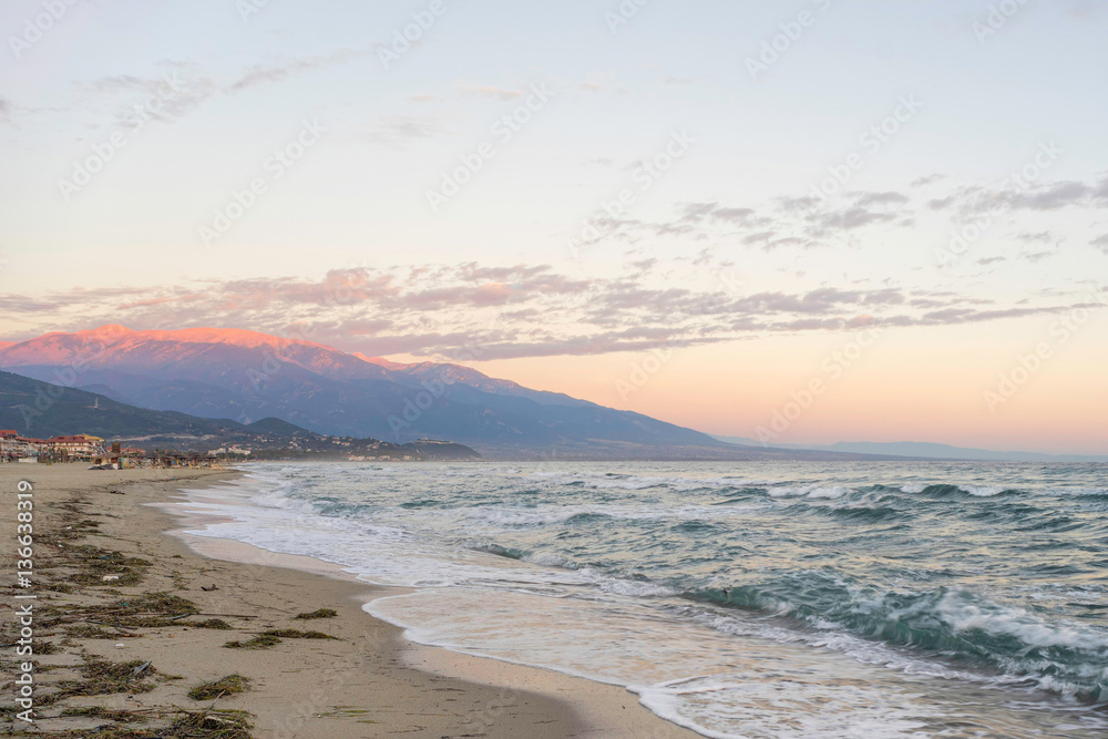 Bright dawn over Mediterranean Sea with long sand beach. Nei Pori village, Pieria, Greece.
