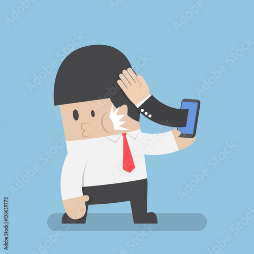Hand sticking out from smartphone and slapped businessman face