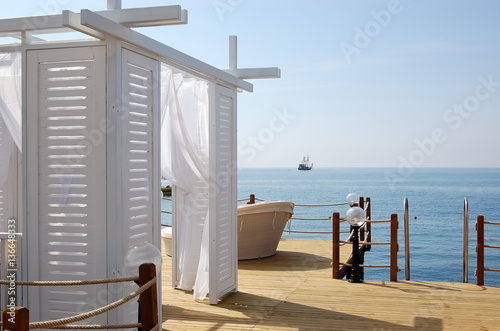 View of white beach tent, ship and blue sea in hotel. photo