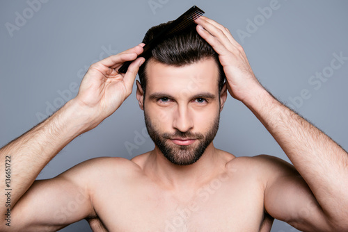 Portrait of handsome young guy combing his hair