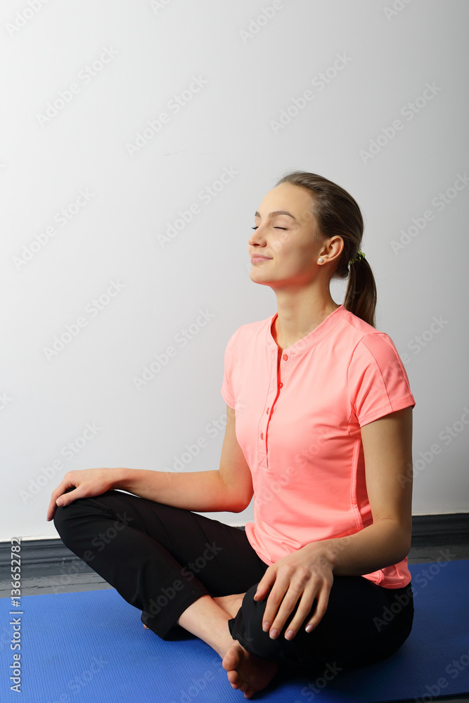Yoga smiling girl sitting with legs crossed, her hands on feets. Yoga smiling girl sitting with legs crossed, her hands on feets.