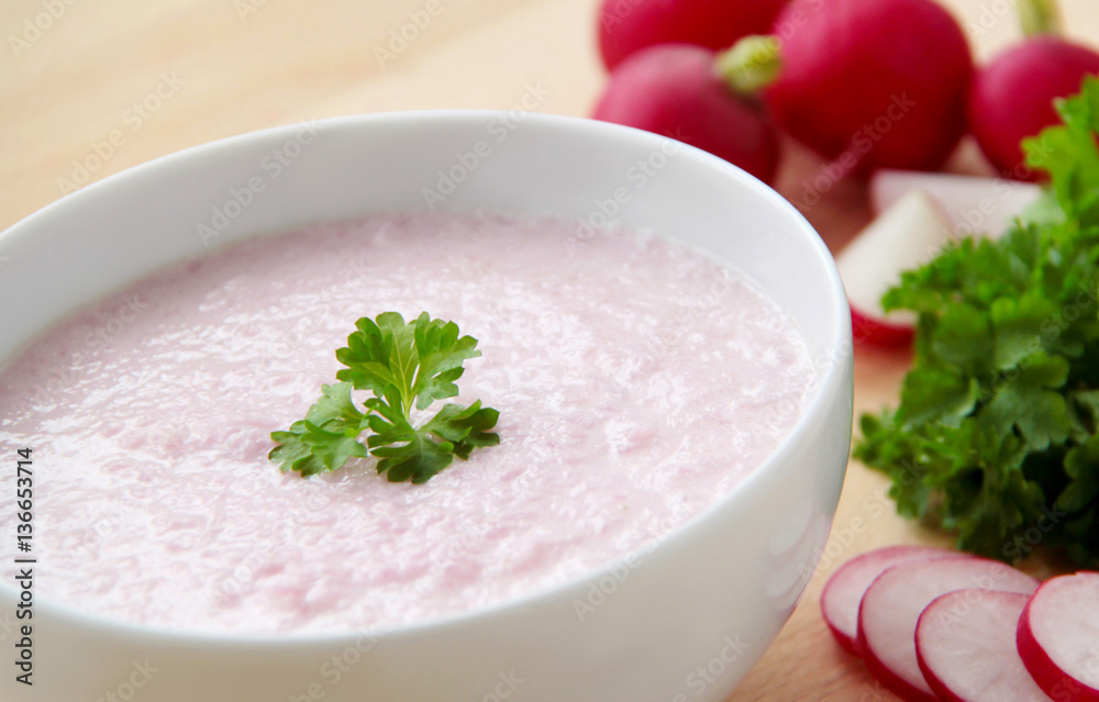 Vegetable spring radish soup. Bowl of radish soup surrounded by ingredients. Wooden background. Closeup view. Vegetable spring radish soup. Bowl of radish soup surrounded by ingredients. Wooden background. Closeup view.