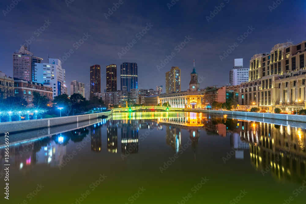 River And Modern Buildings Against Sky at night.