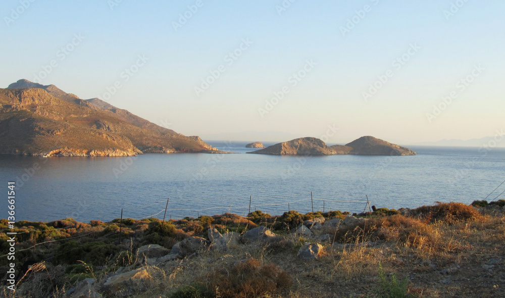 The coast of Tilos island with blue sea and big stack, Greece, at sunrise.