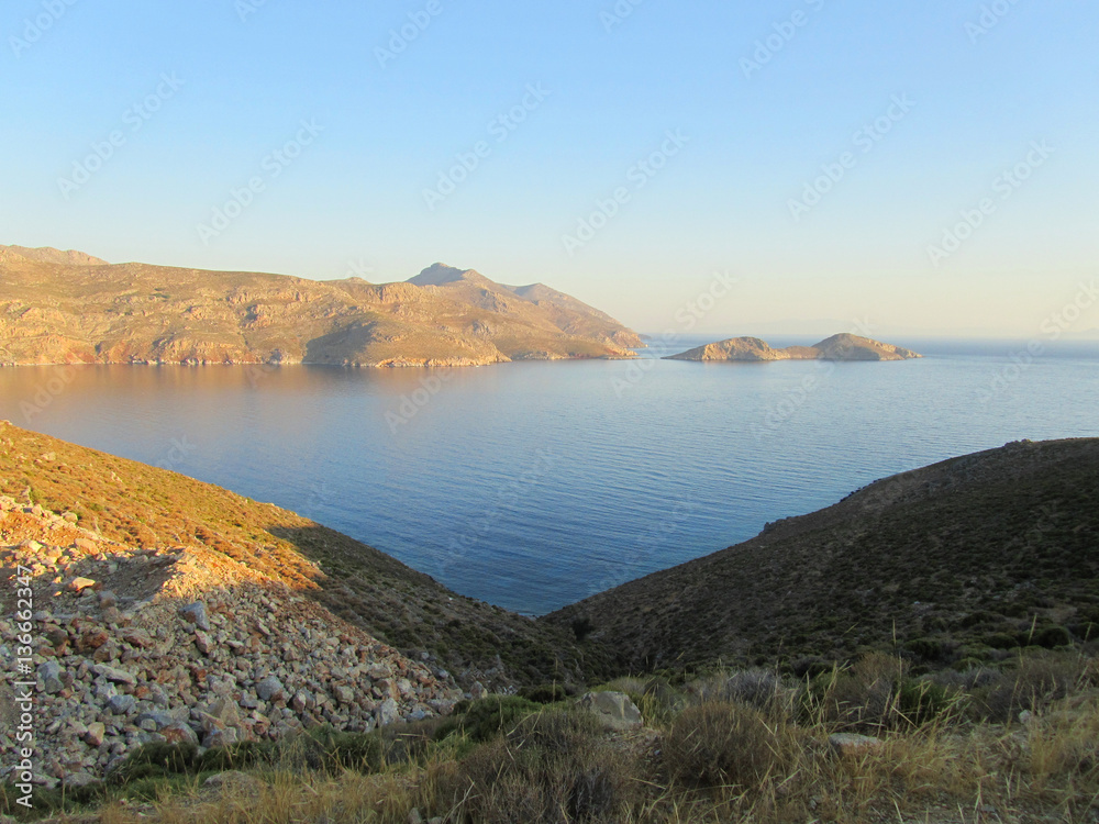 Naklejka premium The coast of Tilos island with blue sea and big stack at sunrise, Greece