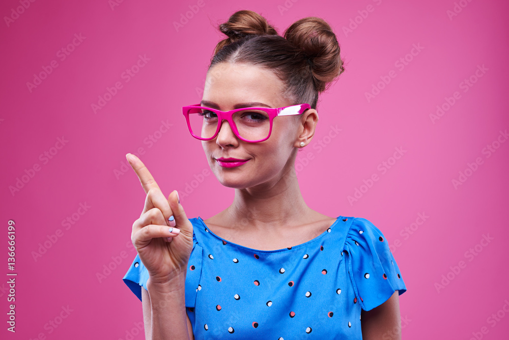 Pensive brunette in pink glasses showing the direction with inde Pensive brunette in pink glasses showing the direction with inde