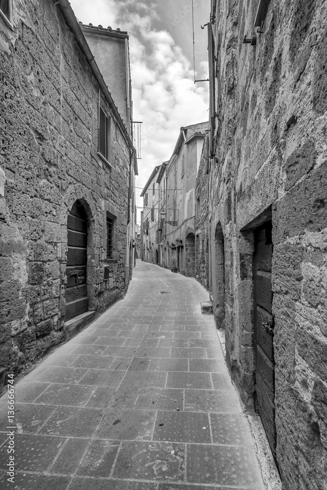 A typical narrow alley in the historic center of Pitigliano, Grosseto, Tuscany, Italy, in black and white