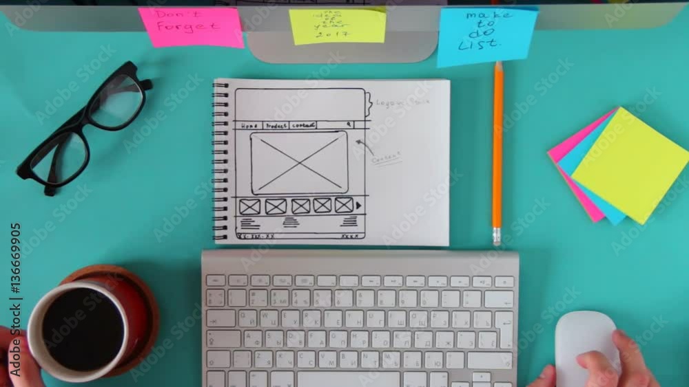 Top view of blue workbench wizard which is web sketch. Man scrolling the mouse and drink coffee.